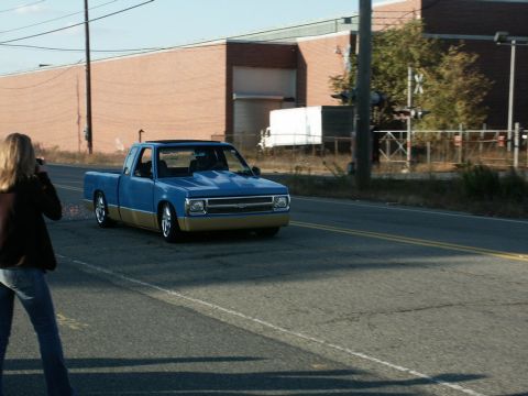 2001 Mercury Grand Marquis - A blue and tan pickup truck is captured in motion on a street, with a woman photographing it from the side.