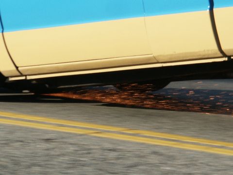 2001 Mercury Grand Marquis - Sparks fly from the undercarriage of a vehicle driving on a road.