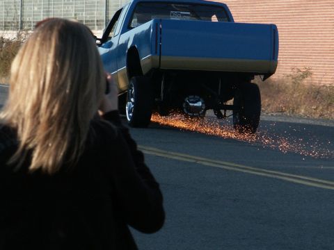 2001 Mercury Grand Marquis - A person films a lifted pickup truck as it performs a burnout, creating a shower of sparks.