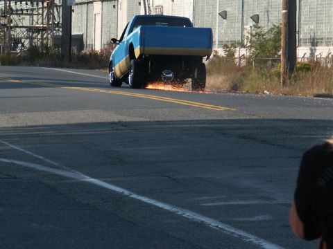 2001 Mercury Grand Marquis - A pickup truck performs a wheelie on a paved road, creating a shower of sparks.