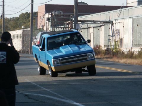 2001 Mercury Grand Marquis - A two-tone pickup truck is seen from the front-right angle on a road, with a person in the foreground looking on.