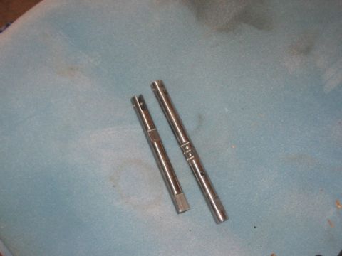 1991 Ford Bronco - Two metal shafts are laid out on a textured blue surface, possibly for repair or replacement.