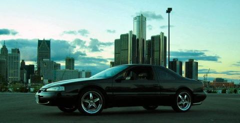 1997 Ford Thunderbird - A black coupe is parked in front of a city skyline at dusk.