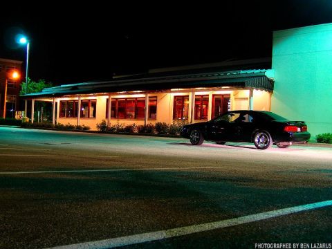 1997 Ford Thunderbird - A black 1997 Ford Thunderbird is parked in front of a building at night.