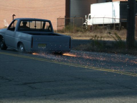 2001 Mercury Grand Marquis - A gray pickup truck is seen from the rear, emitting a shower of sparks as it drives down the road.