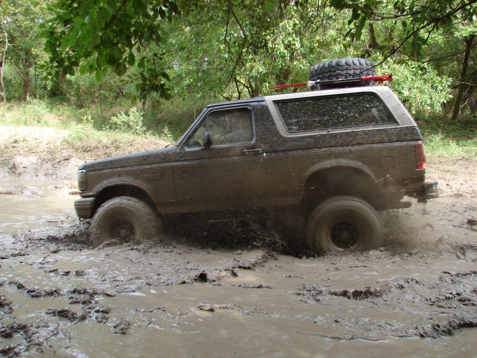 1996 Ford Bronco 3q-front view driving through mud, spare tire on roof rack