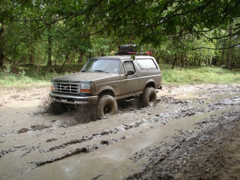 1996 Ford Bronco - Ford Bronco navigating a challenging muddy off-road path.