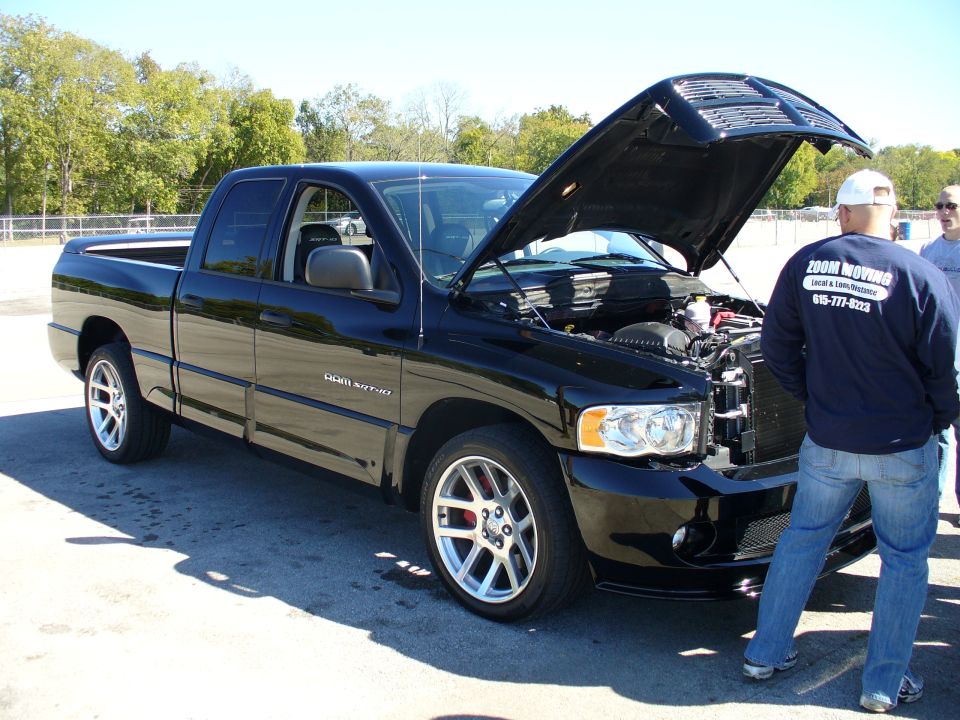 Black Dodge Ram SRT-10 pickup truck with hood open, side view, silver wheels, red brake calipers