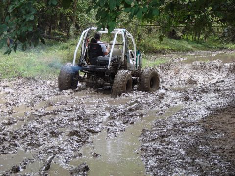 1996 Ford Bronco - A buggy navigates a challenging muddy path, kicking up water and mud as it goes.