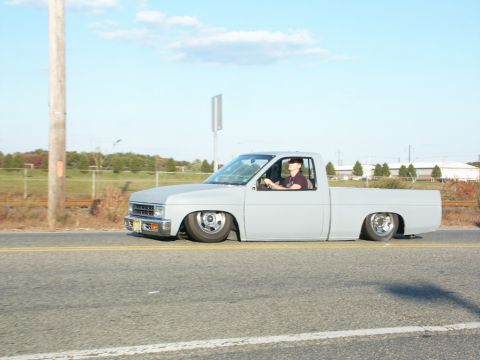 2001 Mercury Grand Marquis - A custom pickup truck with a significantly lowered suspension is seen driving down a road.