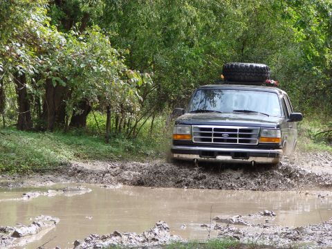 1996 Ford Bronco - 1996 Ford Bronco navigating a muddy off-road trail.