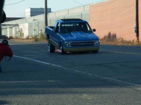 2001 Mercury Grand Marquis - A blue pickup truck is captured in motion on a street, with a photographer in the foreground.