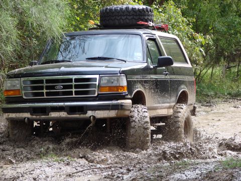 1996 Ford Bronco - This 1996 Ford Bronco is navigating a muddy trail with its tires kicking up water.