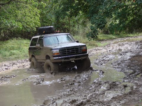 1996 Ford Bronco - Ford Bronco navigating a challenging muddy off-road path.