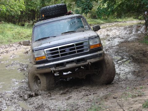 1996 Ford Bronco - This 1996 Ford Bronco is navigating a challenging muddy off-road course, with its front passenger side tire deep in the mire.