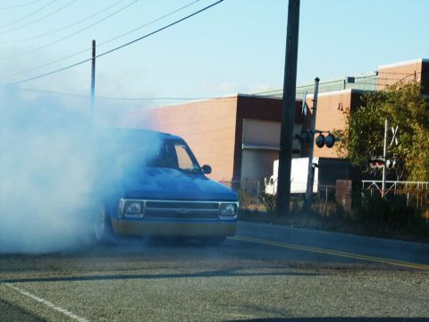 2001 Mercury Grand Marquis - A blue pickup truck is performing a burnout, creating a large cloud of smoke.