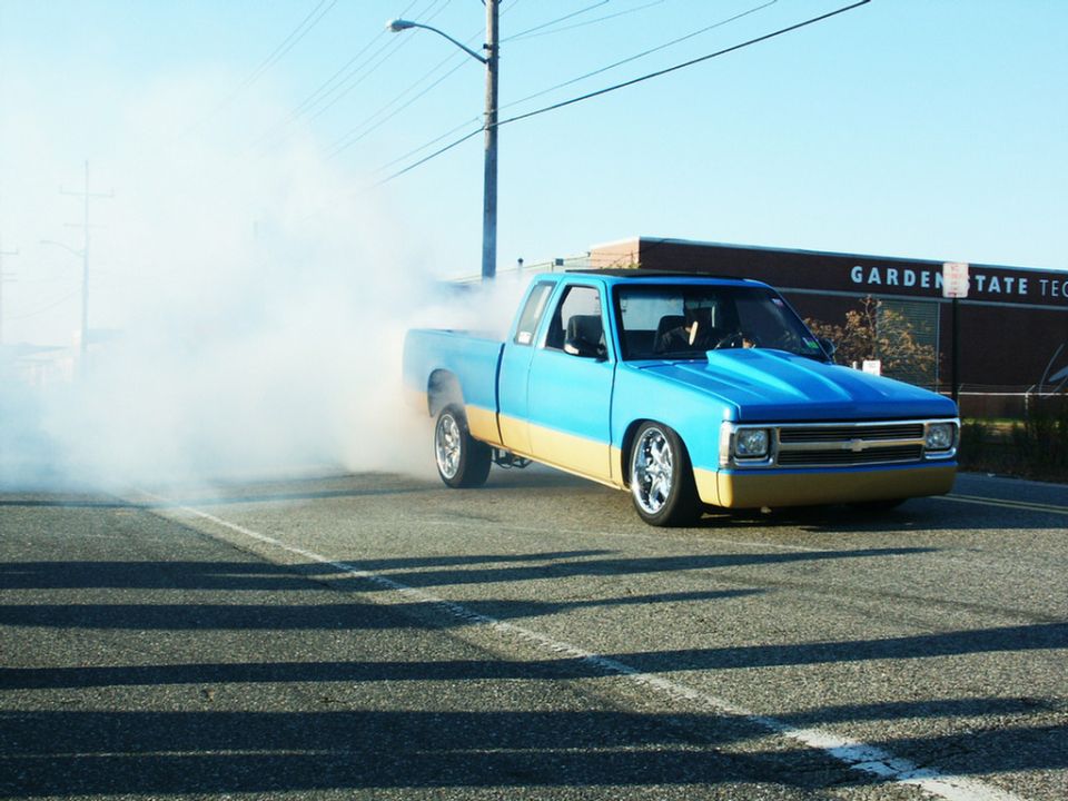 Blue and tan pickup truck doing a burnout, front view
