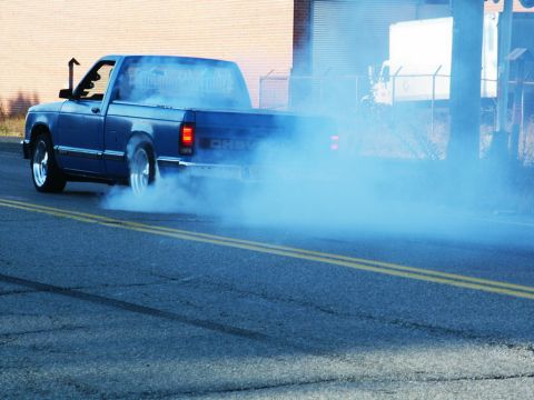 2001 Mercury Grand Marquis - Blue Chevy S-10 pickup truck performing a burnout on a street.
