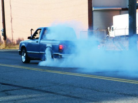 2001 Mercury Grand Marquis - A blue pickup truck is performing a burnout, creating a large cloud of smoke.