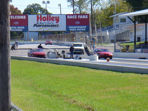 1991 Ford Probe - A red sports car is positioned on a drag strip, ready for a race, with a large Holley billboard in the background.