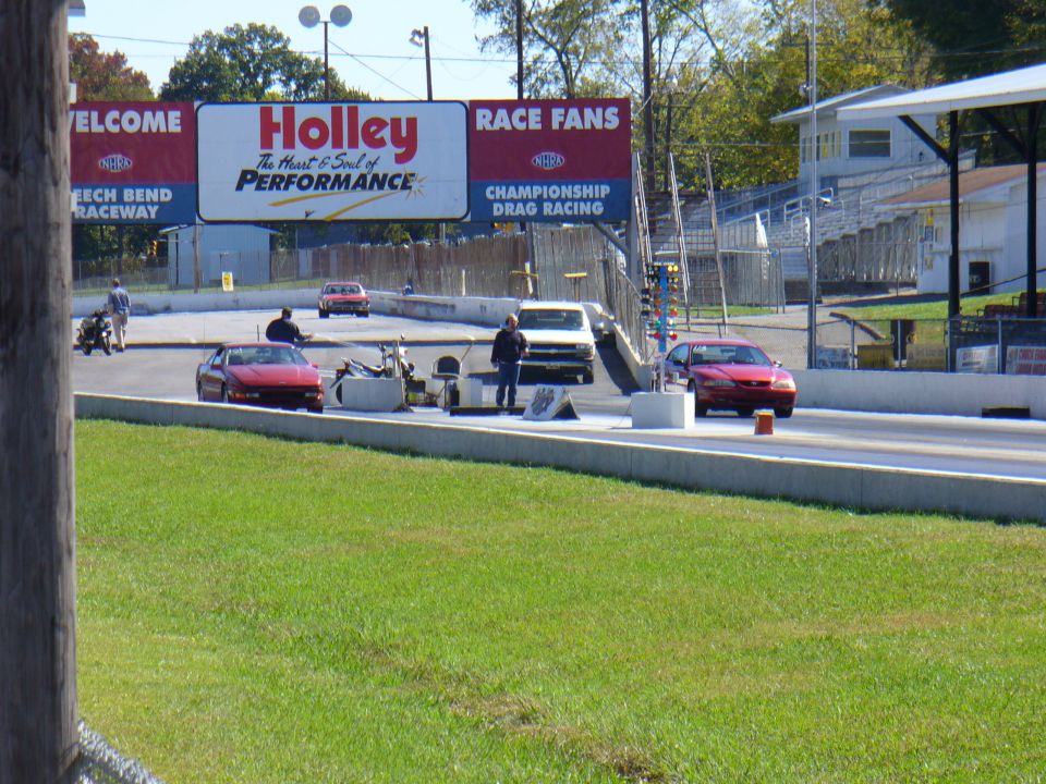 Red sports car on a drag strip, front 3/4 view, low angle. Appears to be a 1990s model