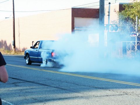 2001 Mercury Grand Marquis - Blue pickup truck performing a burnout, kicking up a large cloud of smoke.