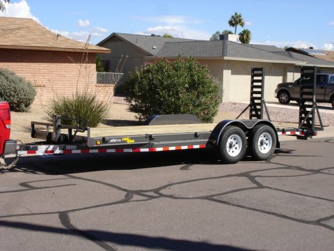 2005 Nissan Titan - A dual-axle trailer is parked on a residential street, with a pickup truck visible in the background.