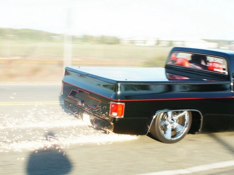 2001 Mercury Grand Marquis - A black pickup truck with custom wheels and red trim emits sparks as it turns on a road.
