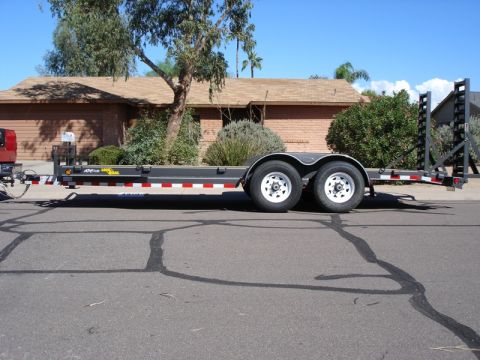 2005 Nissan Titan - A flatbed trailer is viewed from the side, parked on a residential street.