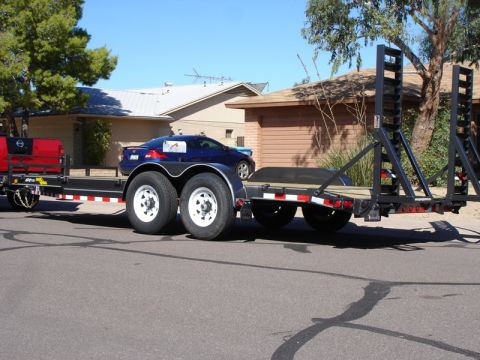 2005 Nissan Titan - A trailer is parked on a street, with a blue car loaded onto it.