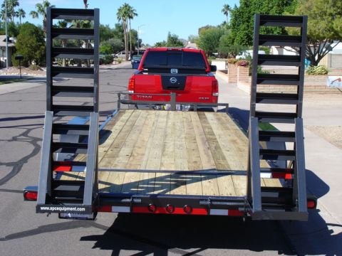 2005 Nissan Titan - A red Nissan Titan pickup truck is hitched to a flatbed trailer, viewed from the rear of the trailer.