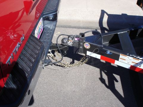 2005 Nissan Titan - Rear view of a red 2005 Nissan Titan pickup truck connected to a trailer.