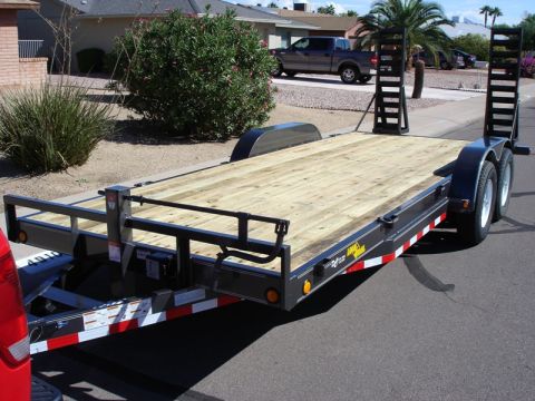 2005 Nissan Titan - A flatbed trailer is parked on a street, with a pickup truck in the background.