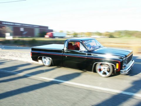 2001 Mercury Grand Marquis - A black pickup truck with a custom lowered stance and red accents cruises down the highway.