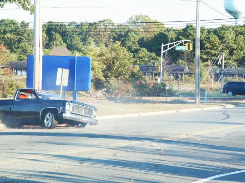 2001 Mercury Grand Marquis - A black pickup truck with a red interior is seen performing a burnout on a road.
