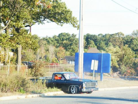 2001 Mercury Grand Marquis - A black pickup truck with an orange interior and lowered suspension is seen parked on the side of the road.