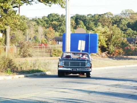 2001 Mercury Grand Marquis - A black pickup truck is seen from the front, carrying a large blue object on its bed.