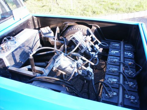 2001 Mercury Grand Marquis - The bed of a blue pickup truck is filled with a complex setup of batteries and air suspension components, along with a spare tire.
