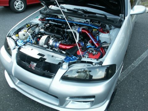 2001 Mercury Grand Marquis - A silver car's engine bay is open, revealing a modified engine with a turbocharger and vibrant red piping. The Supermotors.net logo is visi…