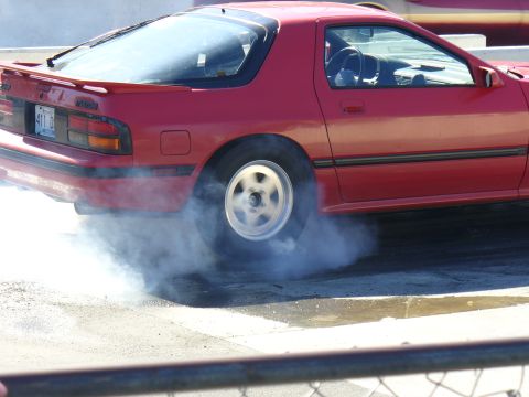 1991 Ford Probe - This red Mazda RX-7 is performing a burnout, creating a cloud of smoke from its rear tire.