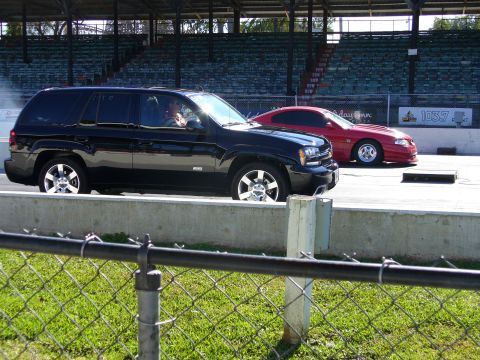 1991 Ford Probe - A red 1994 Ford Mustang GT is seen on a race track next to a black SUV.