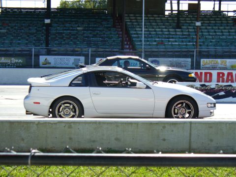1991 Ford Probe - A white Nissan 300ZX is parked on a track next to a black convertible, with stadium seating in the background.
