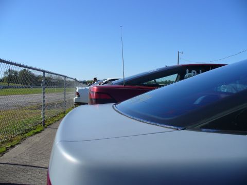 1991 Ford Probe - Several cars are lined up next to a fence, with a clear blue sky overhead.