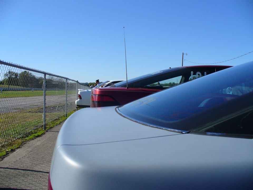 Cars parked next to a chain-link fence on a sunny day