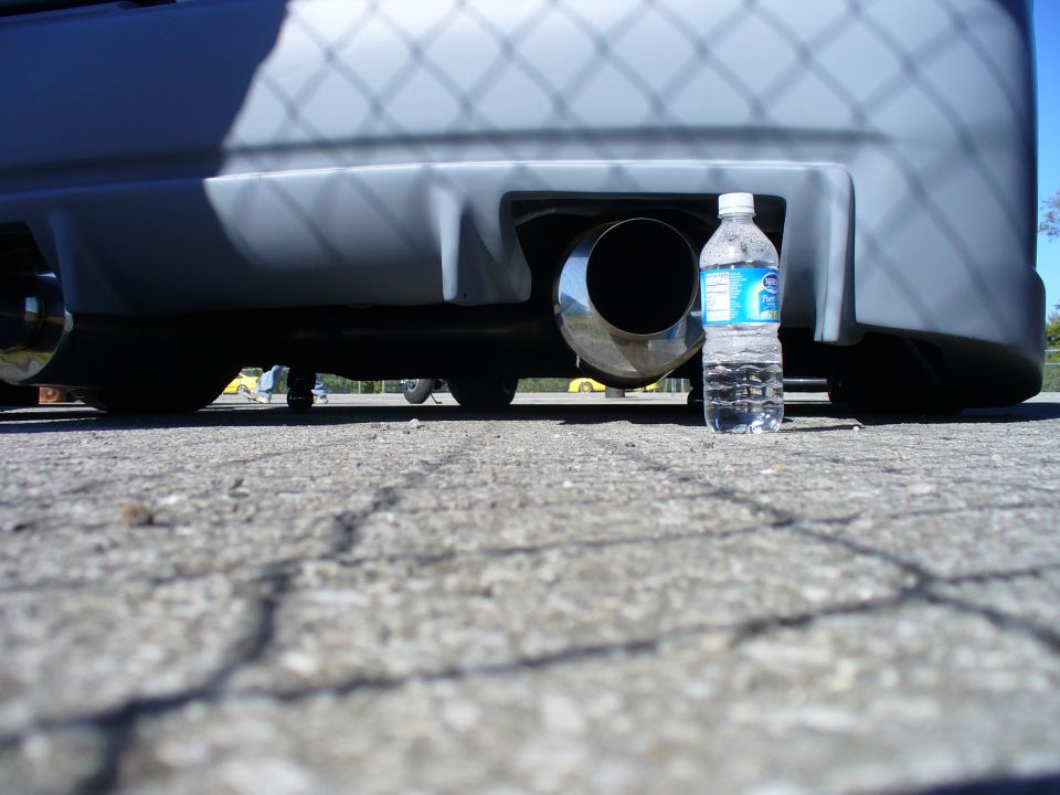 Car's rear bumper with large exhaust pipe, water bottle for scale