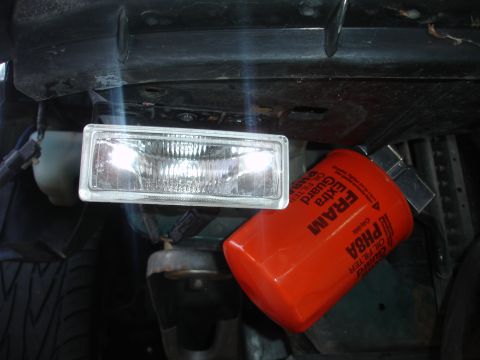 1993 Ford Taurus - A close-up view of a vehicle's front end shows a headlight and an oil filter.