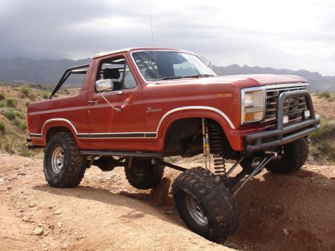 1984 Ford Bronco - Modified Ford Bronco navigating rough terrain with one wheel off the ground.