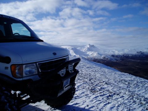 2000 Ford E350 - A Ford E-Series van equipped with a bull bar sits on a snow-covered mountain, overlooking a winter landscape.