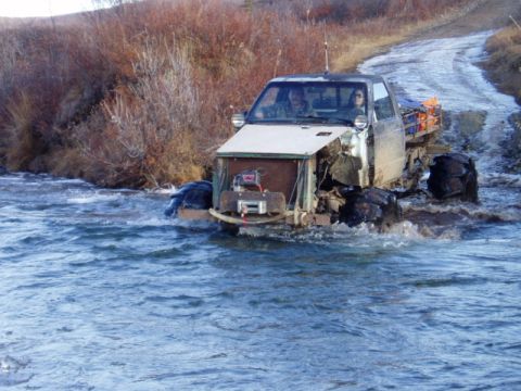 2000 Ford E350 - Modified truck navigates a river crossing on a dirt road, its off-road capabilities.