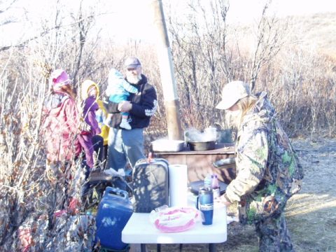 2000 Ford E350 - A family enjoys an outdoor meal preparation with a wood-burning stove and various supplies laid out on a table.